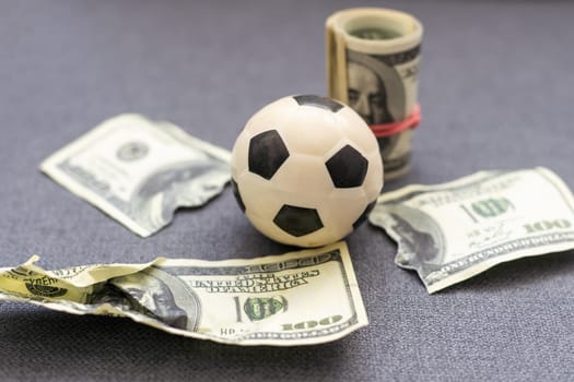 Small soccer ball on heap of dollars isolated on a white background. High quality photo