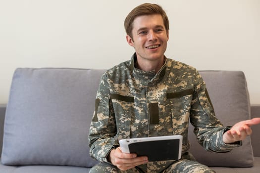 cheerful military man using digital tablet and having video call in office.