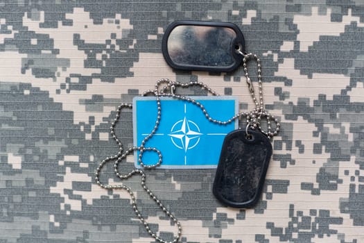 Military ID tags with chain on camouflage uniform, toned in colors of Ukrainian flag war. High quality photo