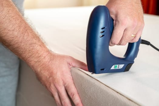 Worker stapling sofa lining with electric staple gun