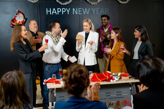 Caucasian manager make surprise by giving the present or gift to his staff on stage during new year party in the hall room of the office.