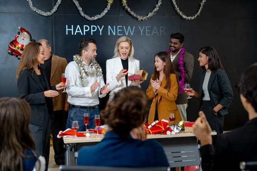 Caucasian manager make surprise by giving the present or gift to his staff on stage during new year party in the hall room of the office.