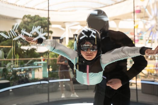 Indoor recreation. teenage girl flying with instructor in indoor wind tunnel. High quality photo