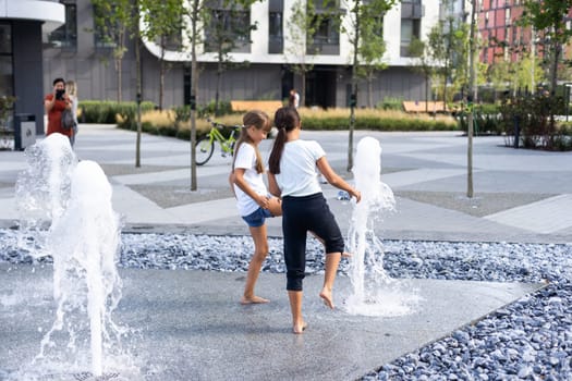 Cute young sisters playing in fountains. Children having fun with water on sunny summer day. Active leisure for kids. High quality photo