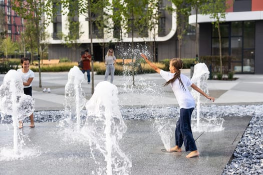 Little girls cool off in a fountain on a hot summer day. High quality photo
