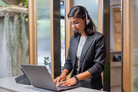 Portrait of Asian business woman wear headphone work with laptop look like customer service stand and focus on her work.