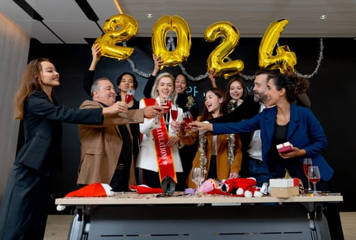 Group of multiethnic business men and women enjoy 2024 new year party together with cheers the wine in hall room of the office.