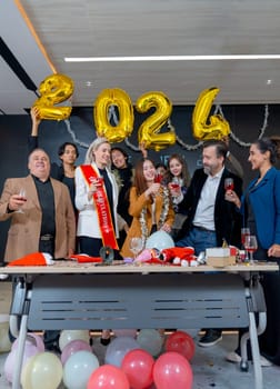 Vertical image of multiethnic business men and women enjoy 2024 new year party together with cheers the wine in hall room of the office.