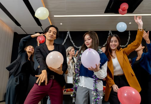 Group of business men and women hold balloon with multiethnic enjoy to dance in new year party in hall room.