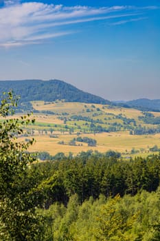 Beautiful green and blue panorama of layers of mountains and trees and some fields seen from top of viewing tower at highest mountain in this area