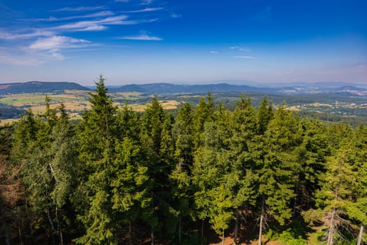 Beautiful green and blue panorama of layers of mountains and trees and some fields seen from top of viewing tower at highest mountain in this area