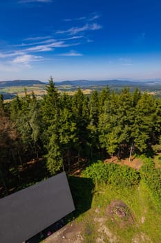 Beautiful green and blue panorama of layers of mountains and trees and some fields seen from top of viewing tower at highest mountain in this area