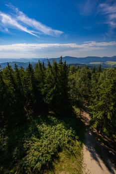 Beautiful green and blue panorama of layers of mountains and trees and some fields seen from top of viewing tower at highest mountain in this area