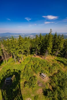 Beautiful green and blue panorama of layers of mountains and trees and some fields seen from top of viewing tower at highest mountain in this area