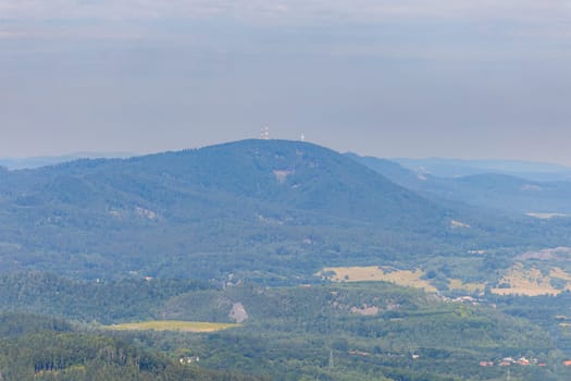 Beautiful green and blue panorama of layers of mountains and trees and some fields seen from top of viewing tower at highest mountain in this area