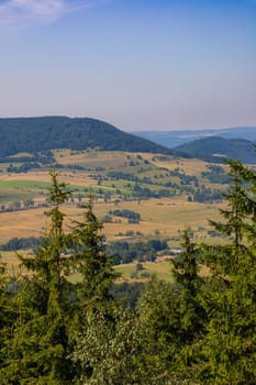 Beautiful green and blue panorama of layers of mountains and trees and some fields seen from top of viewing tower at highest mountain in this area