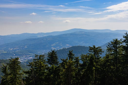 Beautiful green and blue panorama of layers of mountains and trees and some fields seen from top of viewing tower at highest mountain in this area