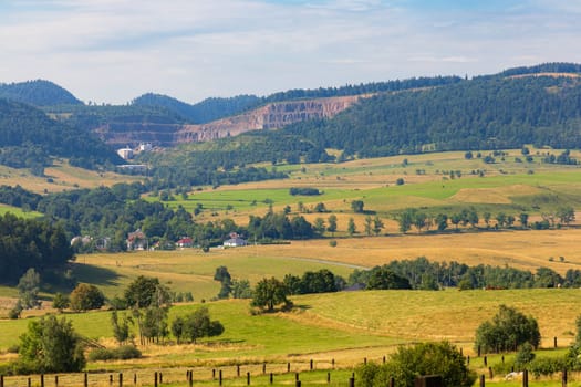 Beautiful landscape of glades and clearing full of fields and trees between it at mountains at sunny cloudy day