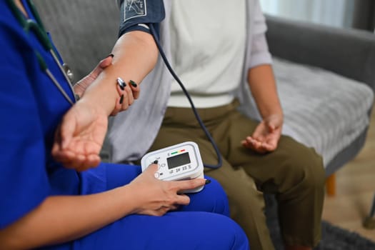 Healthcare worker measuring blood pressure senior woman during home visit. Home health care service concept.