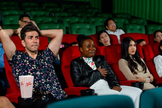 Group of multiethic people sit on seats in cinema theater and they look scary or terify during watch movie.
