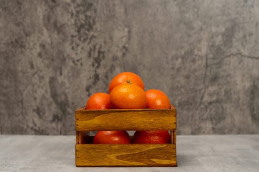 Beautiful wooden basket with some ripe oranges in a still life with a gray background, healthy living concept. Super food rich in vitamin C.