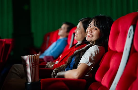 Asian young adult woman sit on cinema seat with her sister and look at camera with smiling in cinema theater in concept of happy and relax activity on holiday or free time.