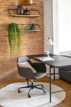 Design furniture bright work area at brick wall and green pot-plant. Area in apartment after renovation for studying or working with modern desk