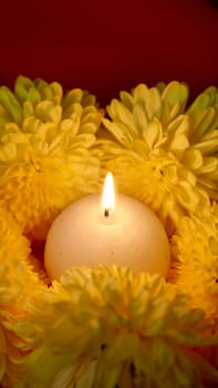 Celebration of the religious Indian festival of Diwali. Yellow flowers with burning holi candles at Hindi festival close-up, vertical