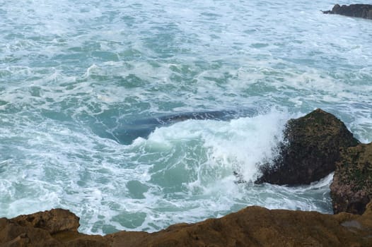 View from of above waves breaking on headland and making splashes and whirlpool. Copy advertising space. Atlantic ocean. Nature background. Waves crashing on the rocks
