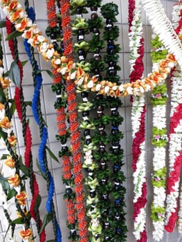 Rows of Colorful Hawaiian flower lei for sale on outdoor wall on Oahu.