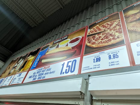Honolulu - December 29, 2022:  Menu board at a Costco food court, with prices and pictures of the available items. The photo shows the hot dog plus, pizza, and drinks sections of the menu, with calorie counts and product information. 