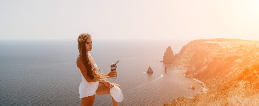 Woman travel sea. Young Happy woman in a long red dress posing on a beach near the sea on background of volcanic rocks, like in Iceland, sharing travel adventure journey