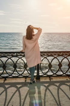 Woman travel sea. Young Happy woman in a long red dress posing on a beach near the sea on background of volcanic rocks, like in Iceland, sharing travel adventure journey