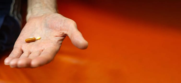 Man old hand holds pills, close-up, selective focus. Banner, copy space