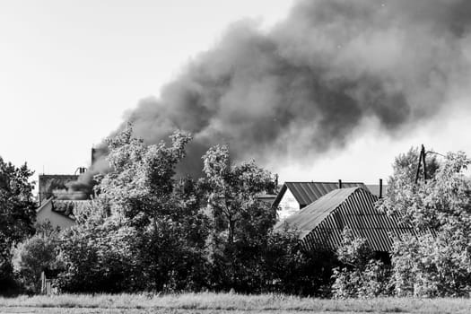 Fire in the city, from buildings and houses, black smoke. Black and white photo