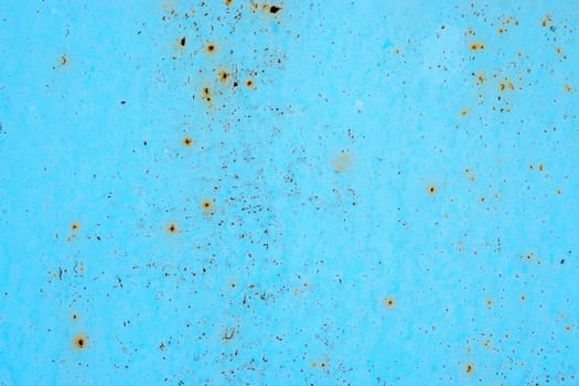 Blue metal surface with spots creating textured wall background