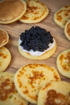 Blinis with black caviar and cream cheese, on a festive dish, mini pancakes, an elegant appetizer, High quality photo