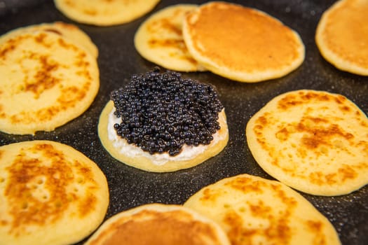 Blinis with black caviar and cream cheese, on a festive dish, mini pancakes, an elegant appetizer, High quality photo