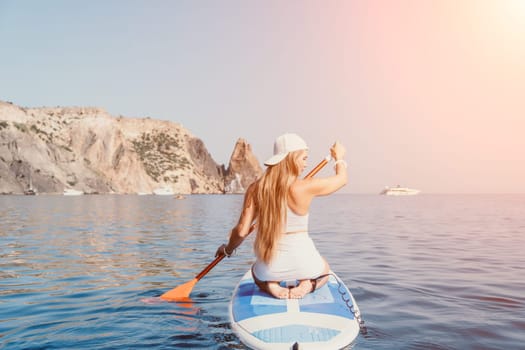 Close up shot of beautiful young caucasian woman with black hair and freckles looking at camera and smiling. Cute woman portrait in a pink bikini posing on a volcanic rock high above the sea