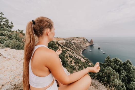 Middle aged well looking woman with black hair doing Pilates with the ring on the yoga mat near the sea on the pebble beach. Female fitness yoga concept. Healthy lifestyle, harmony and meditation.