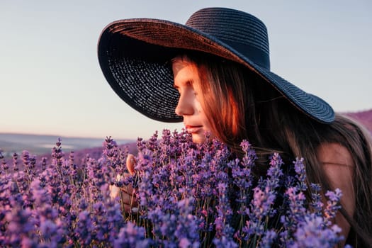 Close up portrait of young beautiful woman in a white dress and a hat is walking in the lavender field and smelling lavender bouquet.