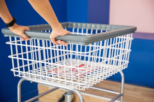 Laundromat convenience store. Woman hands holding empty new white trolley cart, metal cart parked use for laundry at convenience store for support customer