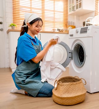 Vertical image of Asian housekeeper or housemaid prepare and check before put white cloth into washing machine during work in customer house.