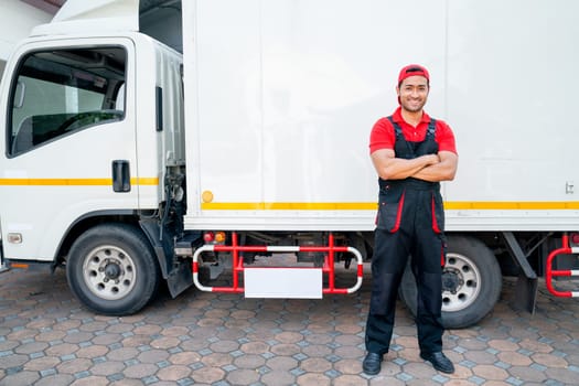 Portrait of Asian delivery man stand beside of truck and arm-crossed also look at camera with smiling after finish to send the product to customer house.