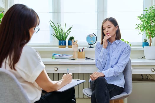 Sad stressed young woman in therapy with professional psychologist. Women talking in office, therapist counselor psychotherapist working with patient. Support, mental health, psychology, psychotherapy