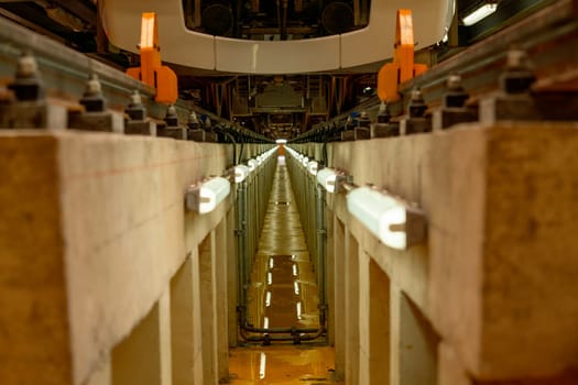 The area under rail of electric train in maintenance center that contain light along the rail that may help support for technician and worker to work.