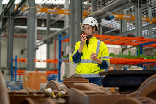 Profession engineer or technician worker use walkie talkie to contact with co-worker or team staff and stand behind part of electric train in maintenance center.