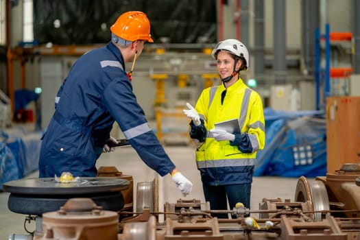 Pretty engineer or factory worker woman hold tablet and explain to technician for the process of maintenance or fix problem of part of electric train in workplace area.