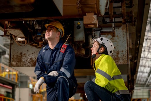 Technician man and train factory worker woman check and fix the problem and stay under electric train in maintenance center.