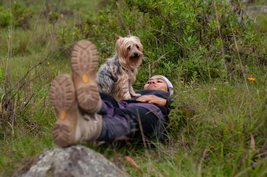 backpacker woman lying on the grass playing with her pet. High quality photo